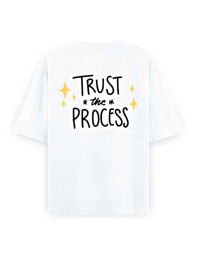 White oversized t-shirt with 'Trust the Process' graphic and yellow star accents on back