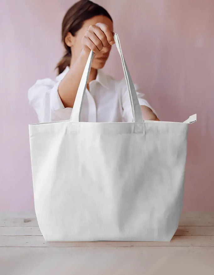 Woman holding large plain white canvas tote bag on wooden table