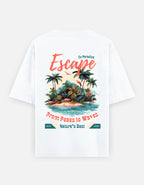 White short-sleeve T-shirt shown flat against a light gray background, featuring a large tropical beach graphic on the front with palm trees, a small island, and coral text reading 'Escape' and 'From Peaks to Waves' plus 'Nature's Best'.