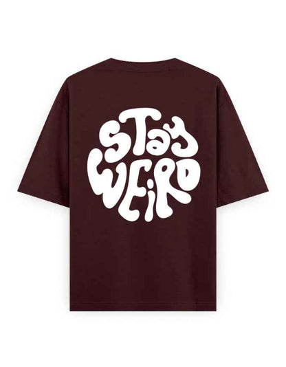 Oversized maroon streetwear t-shirt with bold white 'Stay Weird' graphic on the back