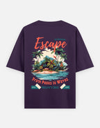 A dark purple short-sleeve t-shirt shown from the back, featuring a colorful graphic print of a tropical island with palm trees, waves, and text reading 'Escape' and 'From Peaks to Waves'.