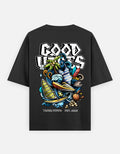 A TREND FEVER black short-sleeve t-shirt with a large, colorful graphic print on the back. The graphic features the text 'GOOD VIBES' in a stylized white font above an illustration of a surfer, waves, a green plant, and other coastal elements.