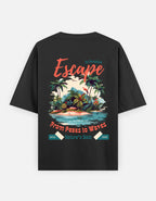 A black short-sleeve t-shirt shown from the back, featuring a colorful graphic print of a tropical island with palm trees, waves, and retro-style text reading 'Escape', 'From Peaks to Waves', and 'Nature's Best'. By Trend Fever