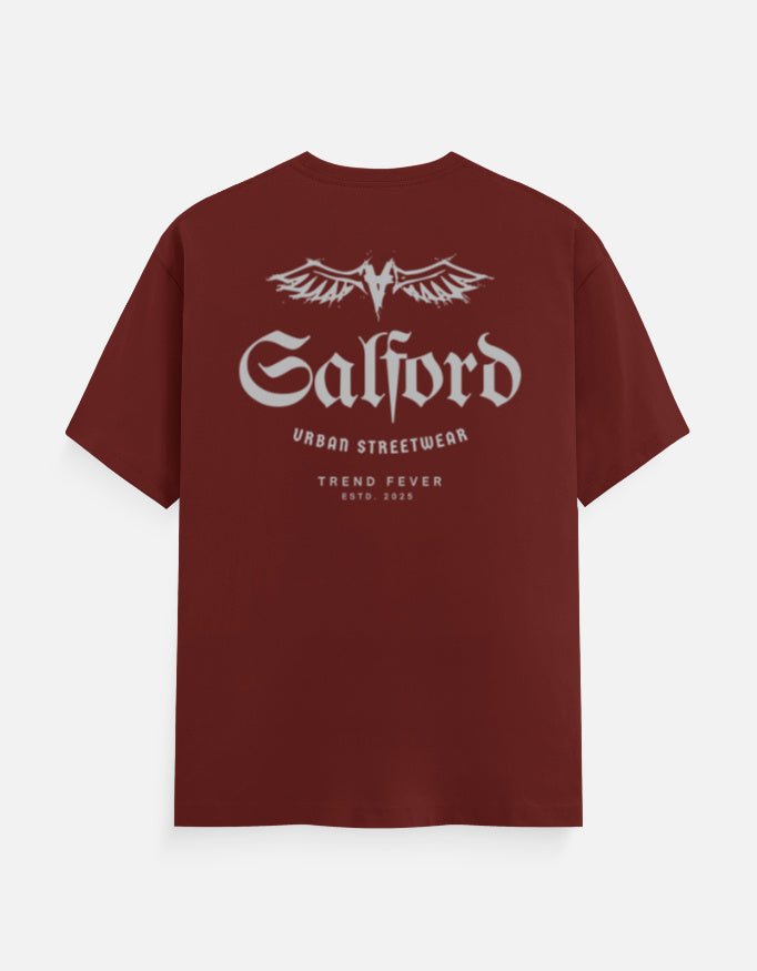 A maroon short-sleeve t-shirt with a white graphic print on the back. The graphic features the word 'Salford' in a gothic font beneath a stylized winged 'S' logo, with 'URBBO STREETWEAR' and 'TREND FEVER ESTD 2020' printed below.