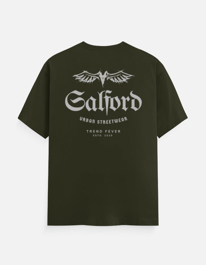 An olive green short-sleeve t-shirt with a white graphic print on the back. The graphic features a stylized winged 'M' logo above the word 'Salford' in a gothic font, with 'URBANO STREETWEAR' and 'TREND FEVER ESTD.