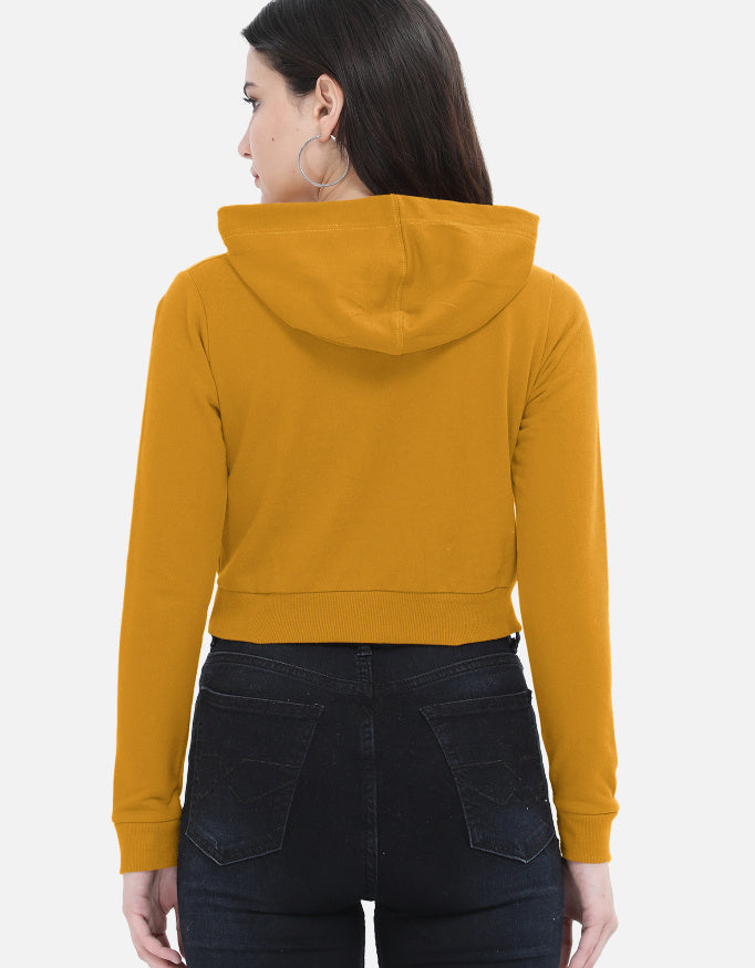 Woman in mustard yellow cropped hoodie and high-waisted black jeans, back view