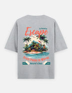 A heather gray short-sleeve t-shirt shown from the back, featuring a colorful graphic print of a tropical island with palm trees, blue water, and coral text reading 'Escape' and 'From Peaks to Waves'.