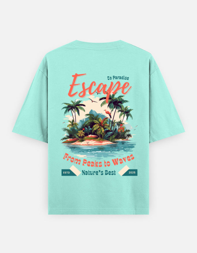 A mint green short-sleeve t-shirt with a colorful graphic print on the back, featuring a tropical island with palm trees, waves, and retro-style text reading 'Escape' and 'From Peaks to Waves'.