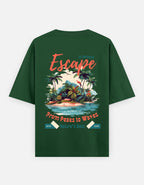 A dark green short-sleeve t-shirt with a large tropical beach graphic on the back. The graphic features the word 'Escape' in coral script, a tropical island scene with palm trees and a sunset, and the text 'From Peaks to Waves' and 'Nature's Best'.