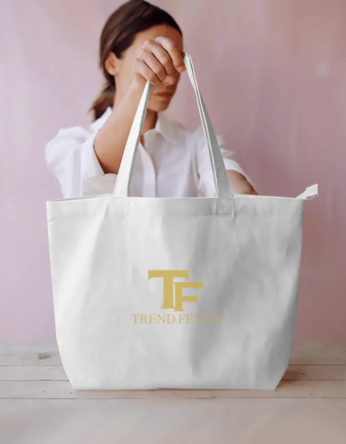 Woman holding a large white tote bag with gold TF Trend Fever logo, casual streetwear style