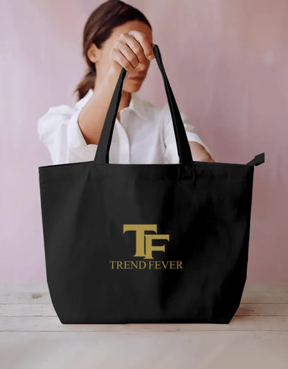 Woman holding large black tote bag with gold TF Trend Fever logo, streetwear accessory