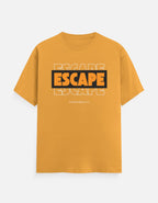A mustard yellow short-sleeve t-shirt with a graphic on the chest reading 'ESCAPE' in orange and black, with 'FROM REALITY' printed below, displayed on a light gray background.