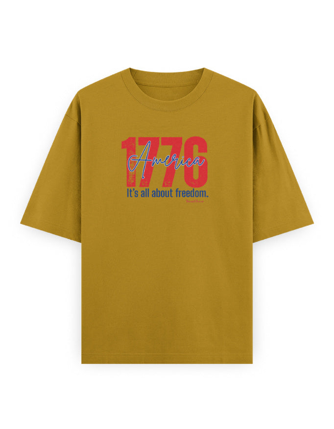 Oversized mustard yellow t-shirt with '1776 America It's all about freedom' graphic print.