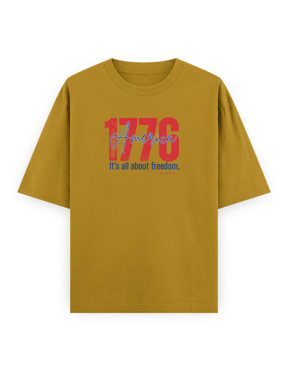Oversized mustard yellow t-shirt with '1776 America It's all about freedom' graphic print.