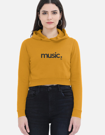 Woman wearing mustard yellow cropped hoodie with 'music.' print, streetwear fashion style