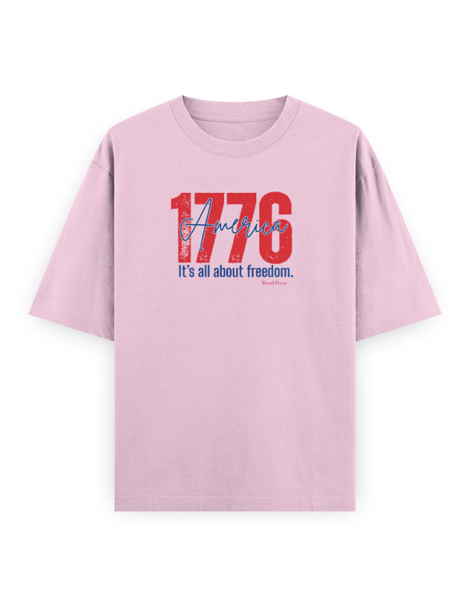 Light pink oversized t-shirt with bold red '1776 America' and 'It's all about freedom' graphic print