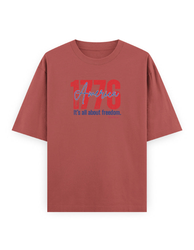 Oversized brown t-shirt with '1776 America It's all about freedom.' graphic print on front.
