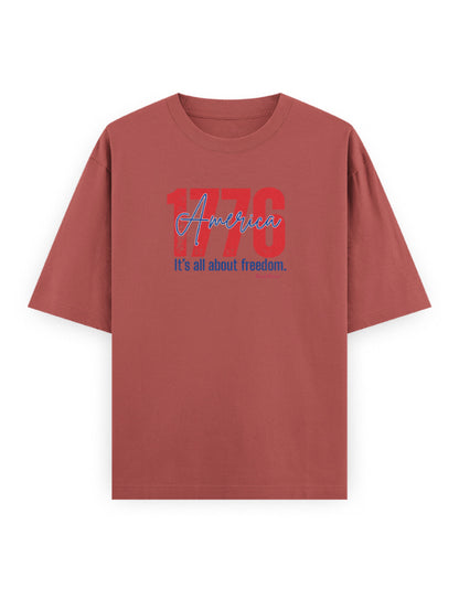 Oversized brown t-shirt with '1776 America It's all about freedom.' graphic print on front.