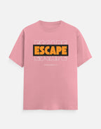 A pink short-sleeve crewneck t-shirt featuring a graphic on the chest with the word 'ESCAPE' in bold yellow letters inside a black rectangle, layered over faint white 'ESCAPE' text, with 'FROM REALITY' printed below in small white letters.