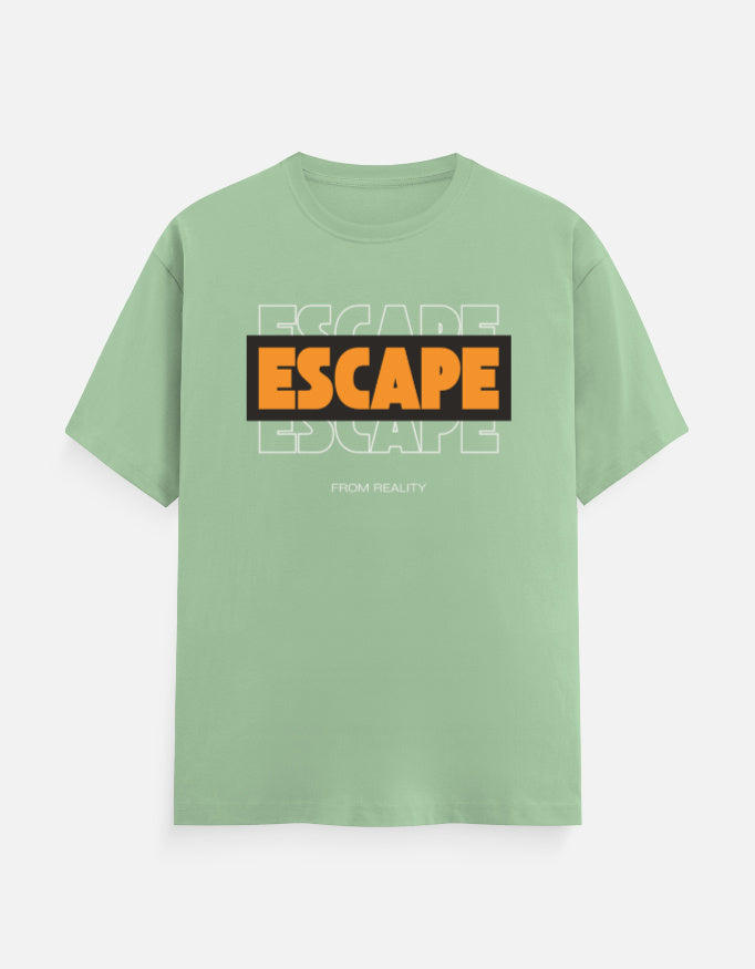 A sage green short-sleeve t-shirt with a graphic on the chest reading 'ESCAPE' in orange and black, layered over faint white 'ESCAPE' text and 'FROM REALITY' below, shown on a light gray background.