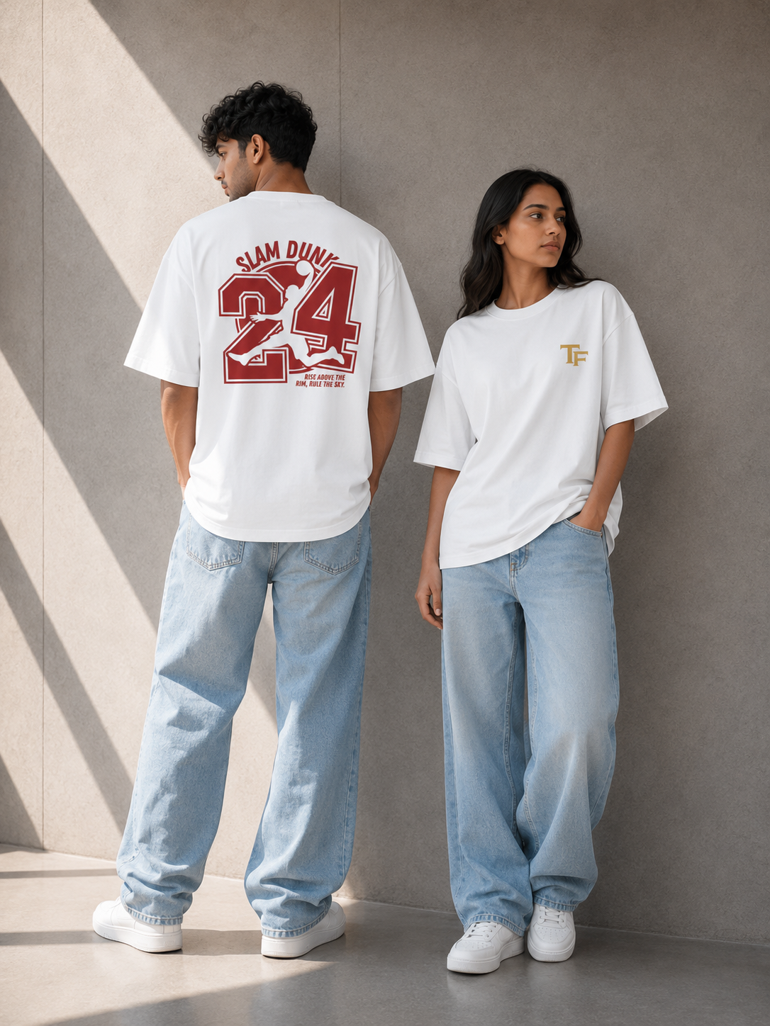 Two models wearing TREND FEVER oversized white graphic T-shirts and light blue jeans, standing against a textured gray concrete wall with diagonal shadows.