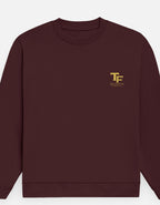 A maroon crewneck sweatshirt with a small gold 'TF' logo and 'Trend Fever' printed on the left chest, displayed against a light gray background.