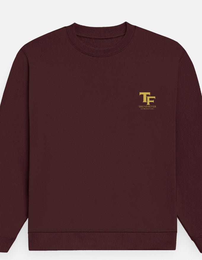 A maroon crewneck sweatshirt with a small gold 'TF' logo and 'Trend Fever' printed on the left chest, displayed against a light gray background.