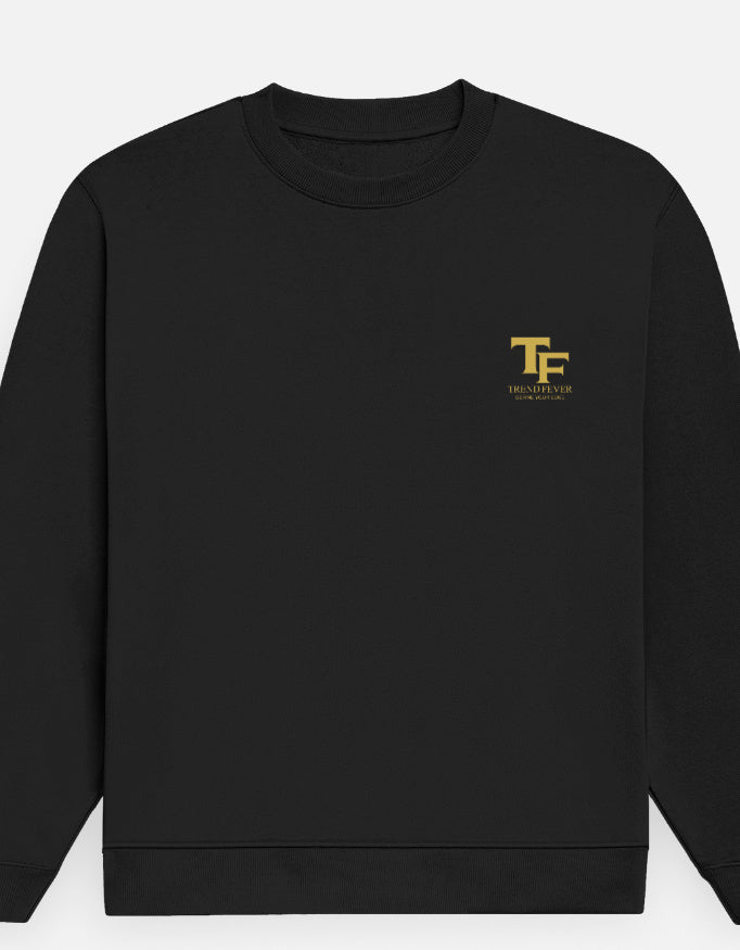 A black crewneck sweatshirt with a small gold 'TF' logo and 'TREND FEVER' printed on the left chest, displayed against a light gray background.