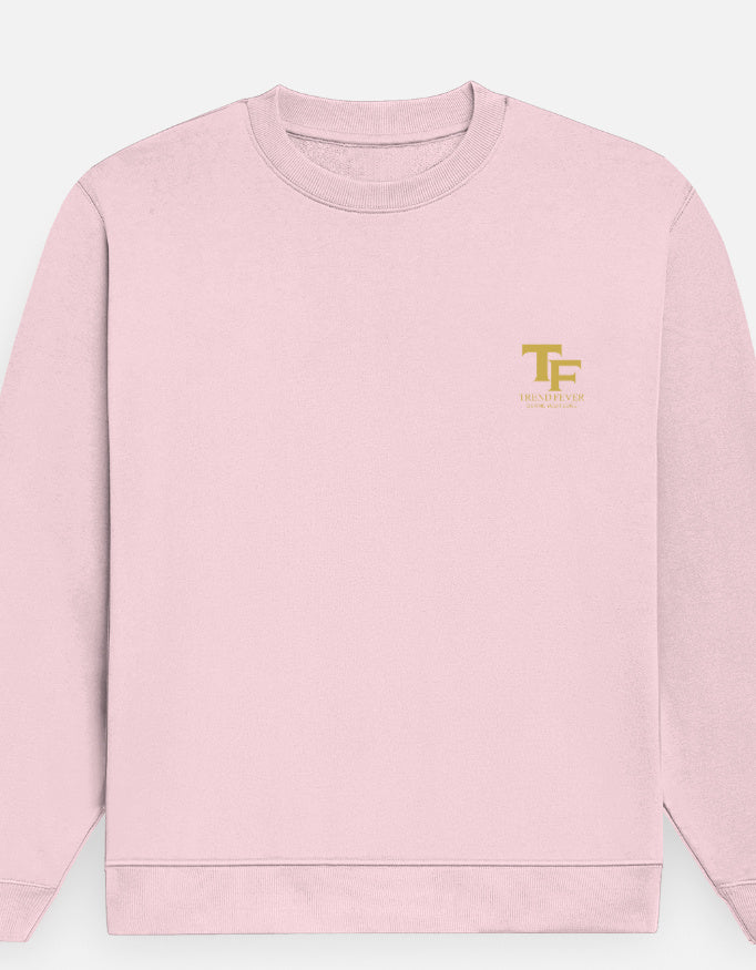 A light pink crewneck sweatshirt with a small gold 'Trend Fever' logo on the left chest, displayed against a light gray background.