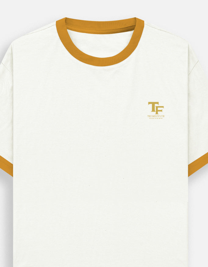 An off-white ringer t-shirt with a mustard yellow crew neck and sleeve trim, featuring a small gold 'TF' logo with 'TREND FEVER' underneath on the left chest.