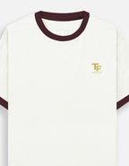 An off-white ringer Trend Fever t-shirt with dark maroon ribbed trim on the crew neck and sleeve cuffs, featuring a small gold embroidered 'TF' logo with 'Trend Fever' on the left chest.
