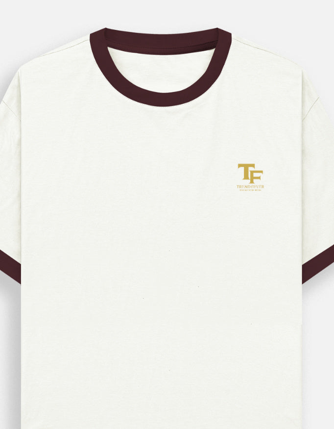 An off-white ringer Trend Fever t-shirt with dark maroon ribbed trim on the crew neck and sleeve cuffs, featuring a small gold embroidered 'TF' logo with 'Trend Fever' on the left chest.